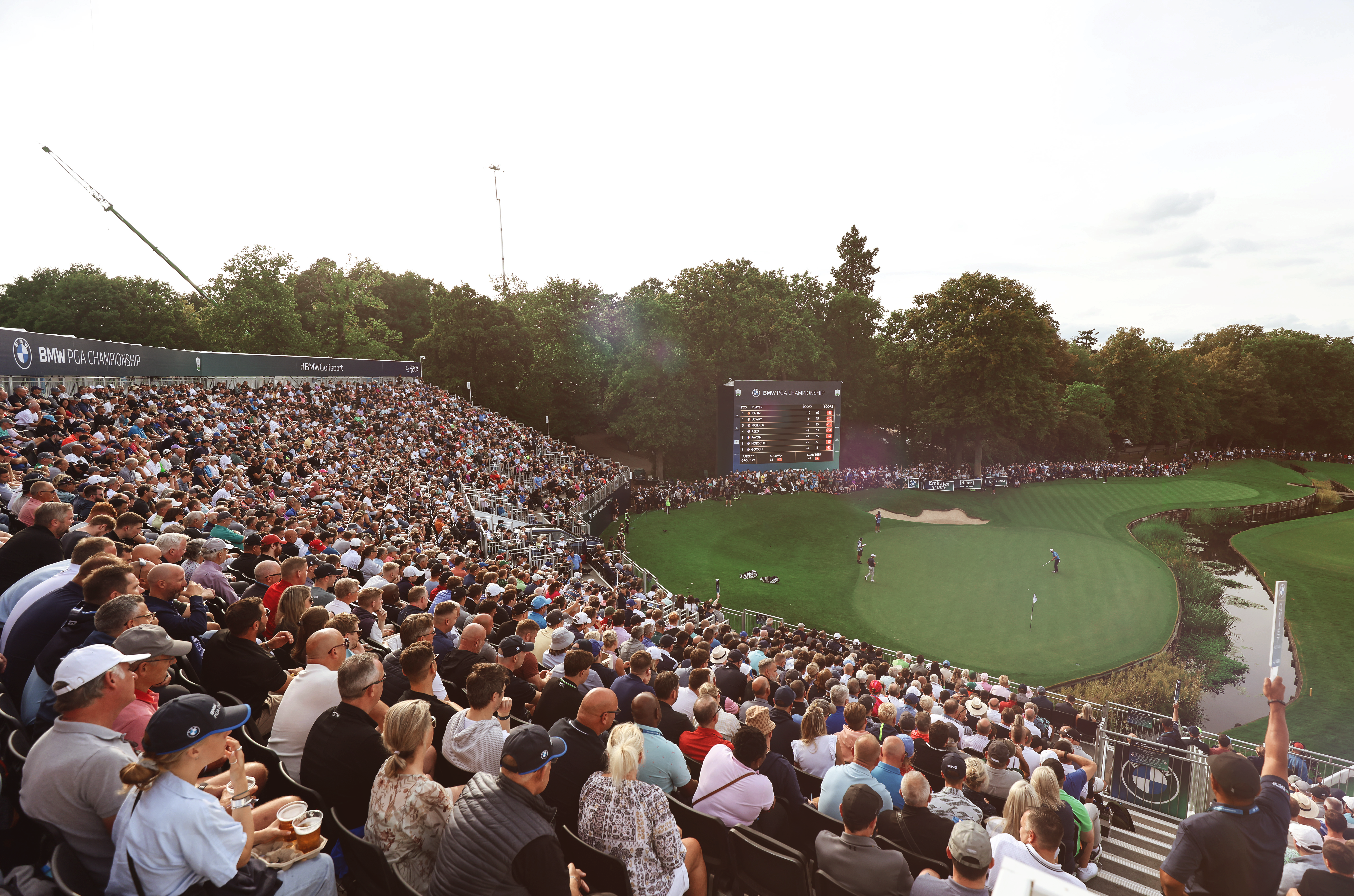 A packed grandstand watches on as players play on the green at the 2022 BMW PGA Championship