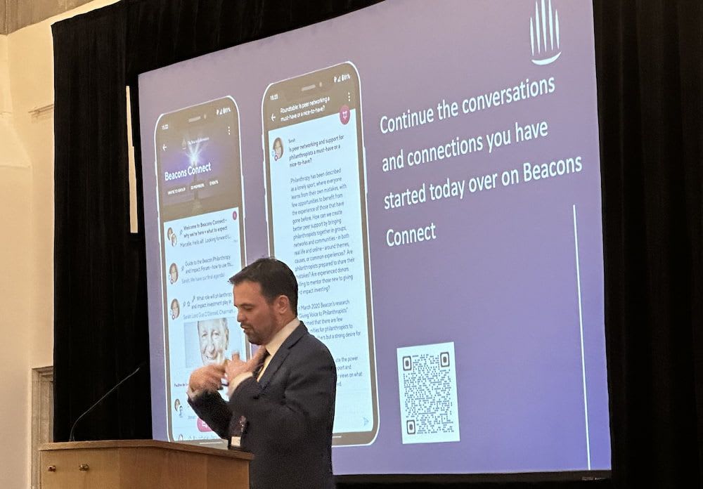 A speaker with a slide behind him showing mobile phone screenshots of the Beacons Connect community on Guild with a QR code to join