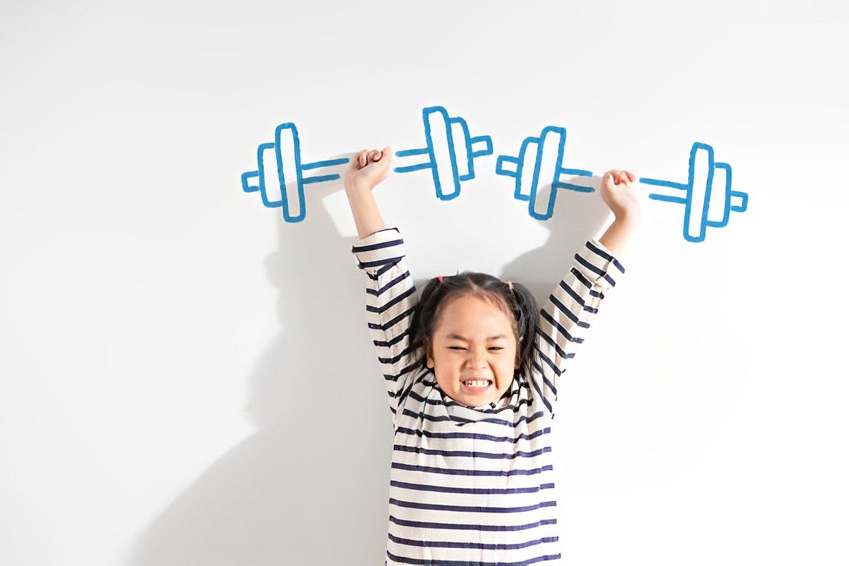 Funny Positive strong  little toddler kid girl lifting weight against the textured white background