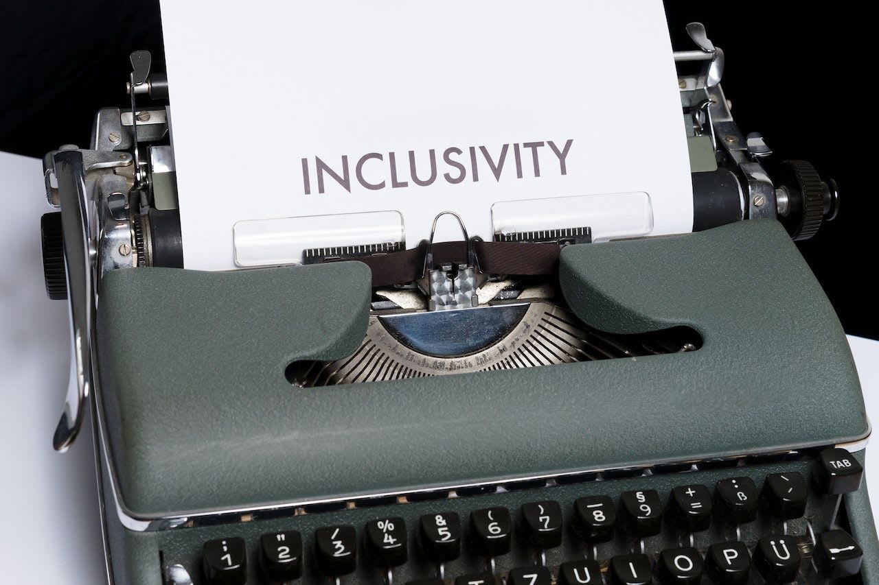 Typewriter with a paper inserted. On the paper, the word inclusivity is written.