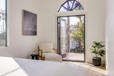 Primary bedroom and French doors opening to a private balcony with seating.