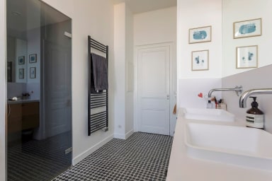 Première salle de bain équipée de 2 vasques, un sèche serviette, une douche...