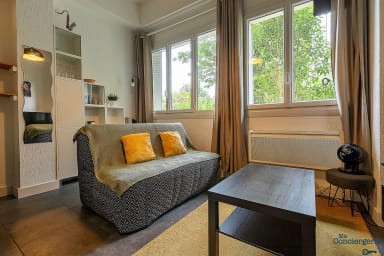 Pièce à vivre avec télé, canapé et fenêtre donnant sur une cour intérieur