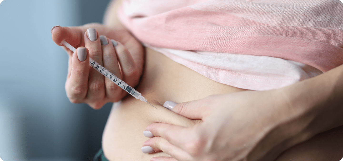 Frau gibt sich eine Spritze in den Bauch