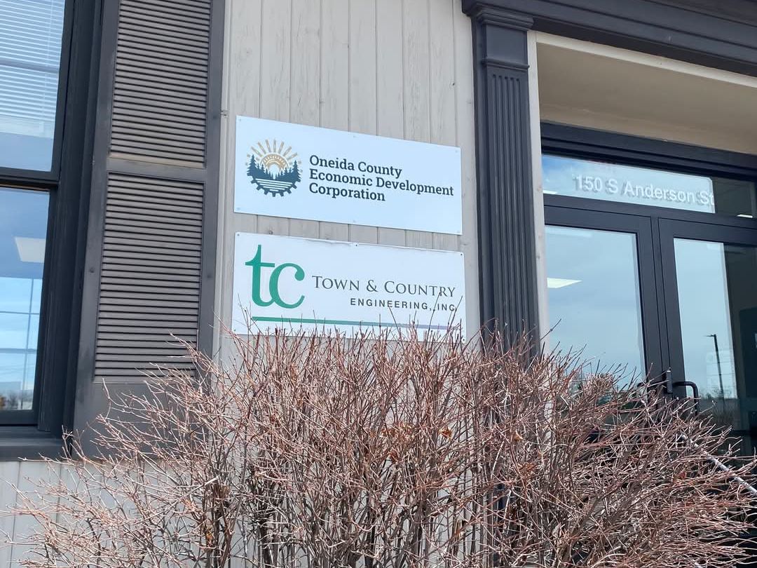 Front view of a building with Oneida County Economic Development Corporation signage above the entrance, next to a leafless shrub
