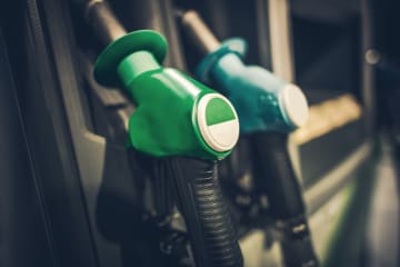 Closeup image of a green gasoline pump nozzle at a gas station