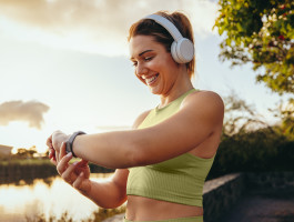 Eine Frau macht Sport im freien und schaut dabei auf ihre Smartwatch.