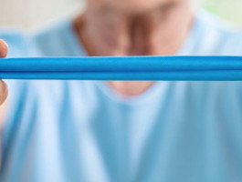 Eine ältere Person spannt ein Theraband zwischen den Händen.