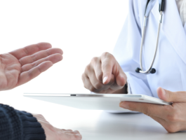 Ärztin mit Stethoskop nutzt Tablet zur digitalen Anamnese, während ein Patient seine Beschwerden schildert – Symbol für moderne Praxissoftware und effiziente digitale Arztpraxis.