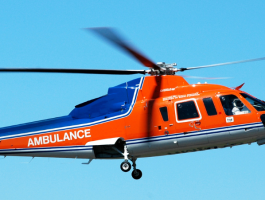 Orange-blauer Rettungshubschrauber (Air Ambulance) im Flug vor blauem Himmel, medizinischer Notfalleinsatz und schneller Patiententransport durch ein spezialisiertes Notfallteam.
