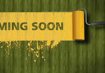 Ein gelber Farbroller malt ein "COMING SOON"-Zeichen auf einen grünen Holzhintergrund. Der Text erscheint auf einem gelben Streifen mit Farbklecksen am Rand. Der Farbroller befindet sich auf der rechten Seite des Bildes.