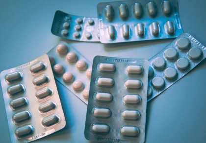 Mehrere Blisterpackungen mit verschiedenen Tabletten und Kapseln liegen auf einem blauen Hintergrund. Die Packungen enthalten weiße und cremefarbene Medikamente in unterschiedlichen Formen und Größen.
