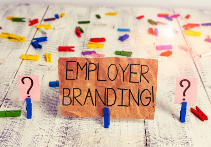 Ein handgeschriebenes Schild mit der Aufschrift "EMPLOYER BRANDING!" ist in der Mitte des Bildes zu sehen, befestigt an einer blauen Wäscheklammer.