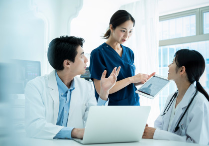 Die Praxismanagerin bespricht Aufgaben mit Arzt und Ärztin.