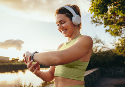 Eine Frau macht Sport im freien und schaut dabei auf ihre Smartwatch.