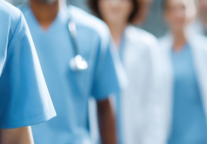 Medizinisches Fachpersonal in Klinikflur: Mehrere Ärztinnen und Ärzte sowie Pflegekräfte in Berufskleidung stehen nebeneinander. Symbolbild für Ärztemangel, Personalknappheit und Herausforderungen im Gesundheitssystem.