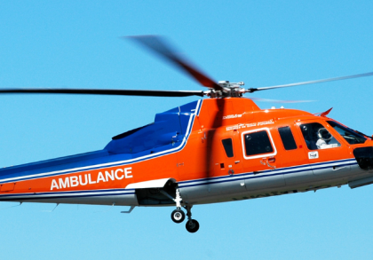 Orange-blauer Rettungshubschrauber (Air Ambulance) im Flug vor blauem Himmel, medizinischer Notfalleinsatz und schneller Patiententransport durch ein spezialisiertes Notfallteam.