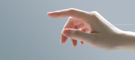 Eine Nahaufnahme einer Hand mit ausgestrecktem Zeigefinger vor einem grauen Hintergrund.