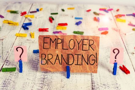 Ein handgeschriebenes Schild mit der Aufschrift "EMPLOYER BRANDING!" ist in der Mitte des Bildes zu sehen, befestigt an einer blauen Wäscheklammer.