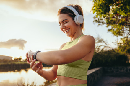 Eine Frau macht Sport im freien und schaut dabei auf ihre Smartwatch.