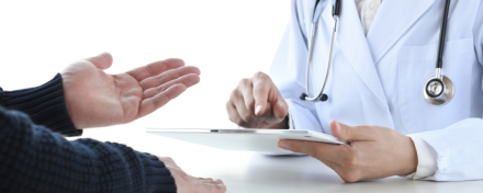 Ärztin mit Stethoskop nutzt Tablet zur digitalen Anamnese, während ein Patient seine Beschwerden schildert – Symbol für moderne Praxissoftware und effiziente digitale Arztpraxis.