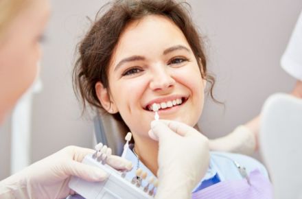 Eine Frau beim Zahnarzt. Anpassung der Zahnfarbe mit Schablonen.