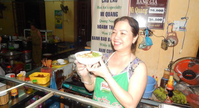 An einem Streetfood Stand serviert eine Marktfrau vietnamesisches Essen