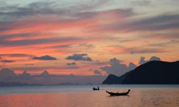 a sunset over a body of water with a mountain in the background