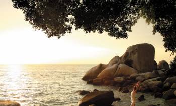 a group of people sitting on a rock next to a body of water