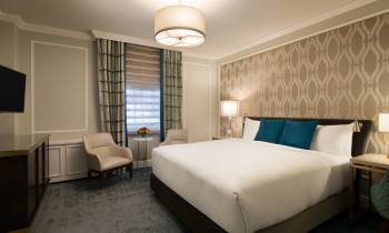 a bedroom with a bed and desk in a hotel room