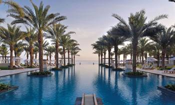 a pool next to a body of water surrounded by palm trees