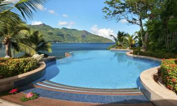 a pool next to a body of water surrounded by palm trees