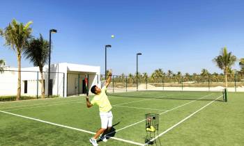 a man holding a football ball on a court with a racket