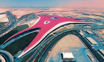 a train is parked on the beach with Ferrari World Abu Dhabi in the background