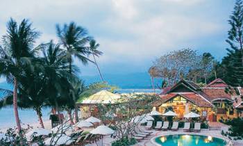 a pool next to a body of water surrounded by palm trees
