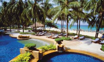 a pool next to a body of water surrounded by palm trees