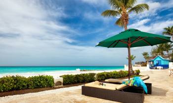 a couple of lawn chairs sitting on top of a sandy beach