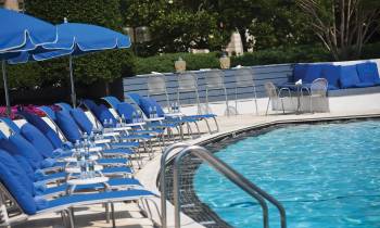 a row of lawn chairs sitting next to a pool of water
