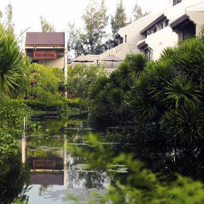 a house with bushes in front of a pond