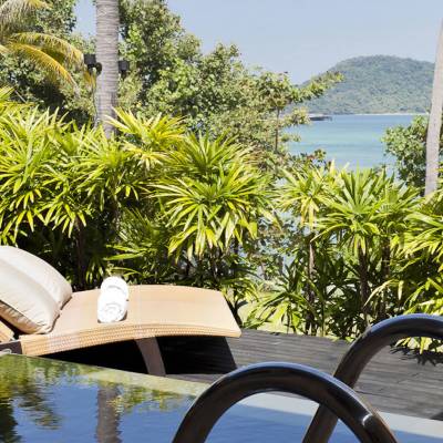 a chair sitting in front of a palm tree and water