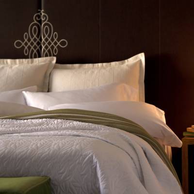 a large white bed sitting next to a lamp
