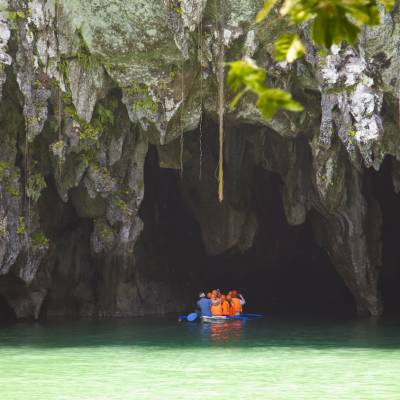 a boat sitting on top of a rock with Puerto Princesa Subterranean River National Park in the background