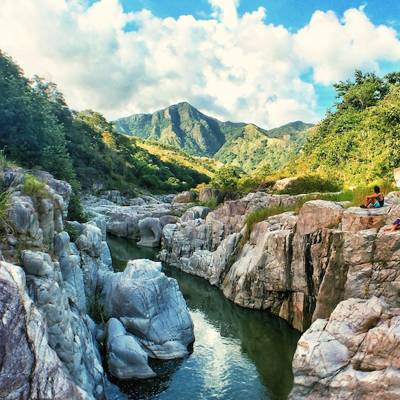 a rocky river with trees on the side of a mountain