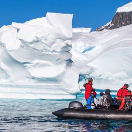 Enchanting Travels Antarctica Tours Boat full of tourists explore huge icebergs