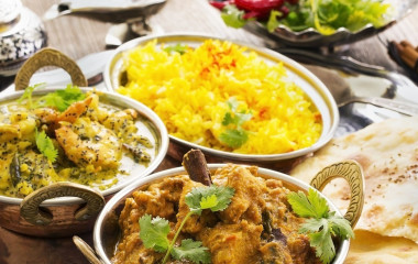 Schälchen von indischen Gerichten wie Curry, Reis und Naan