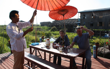 Touristen sitzen auf einer Terrasse von Pfahl-Häusern am Inle-See in Myanmar