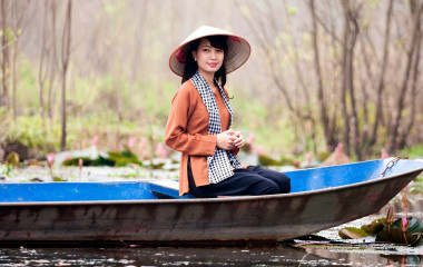 Junge Frau mit Strohhut sitzt im Kanu in Vietnam