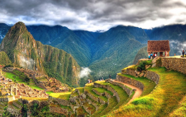 HDR-Panorama von Machu Picchu mit Terrassen, vereinzelten Besuchern und bewölktem Himmel in Peru