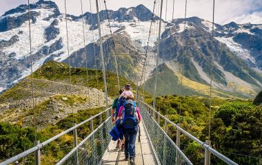 Amazing Nature of Hooker Valley Track in Mount Cook, New Zealand. Young Family walk on Suspension Bridge