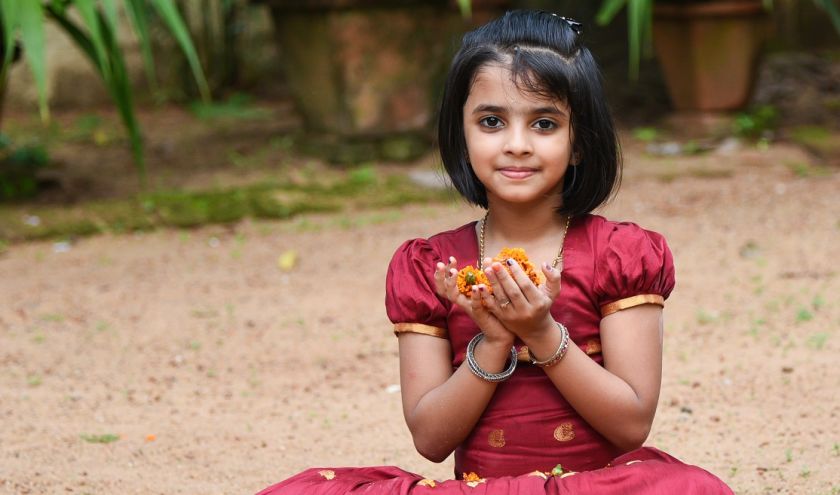 Girl holding flower in hand during Onam Festival Kerala Tour